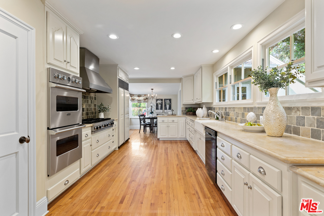 1110 Stradella Road Los Angeles, CA 90077 - Photo 9 of 28 a large kitchen with stainless steel appliances large white cabinets and wooden floor
