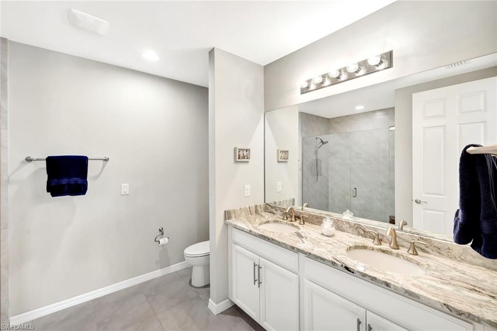 14863 Edgewater Circle Naples, FL 34114 - Photo 12 of 35 a bathroom with a granite countertop sink a toilet and a large mirror