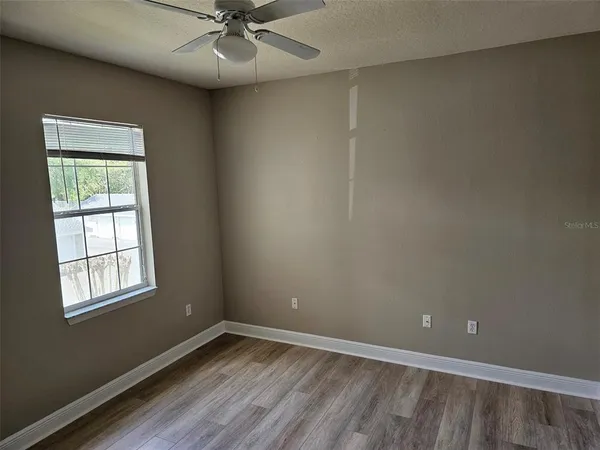 an empty room with a window and a fan