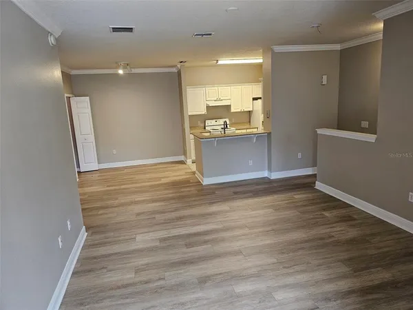 a view of kitchen and empty room with wooden floor