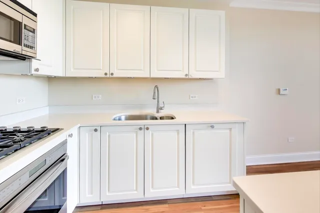 a kitchen with white cabinets and sink