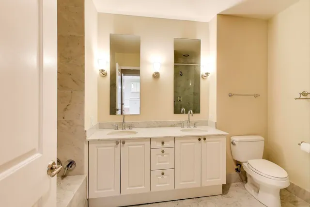 a bathroom with a granite countertop toilet sink and mirror
