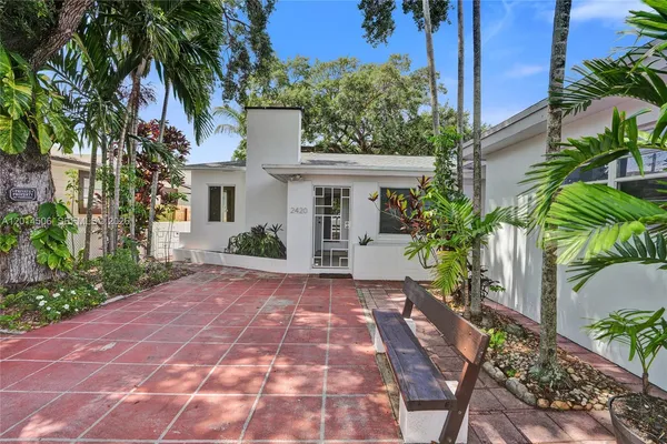 a view of a white house with a yard and plants
