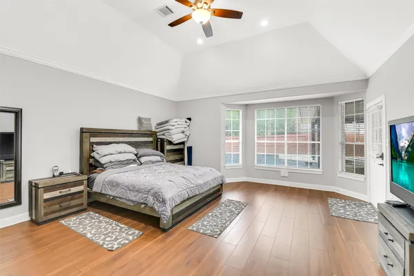 a bedroom with a bed and a large window with wooden floor