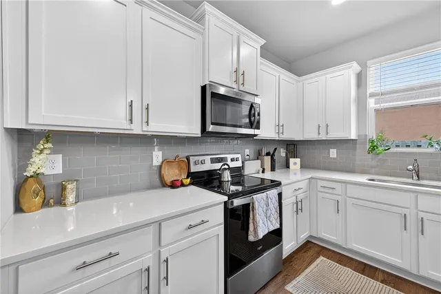 a kitchen with stainless steel appliances granite countertop white cabinets a sink and dishwasher