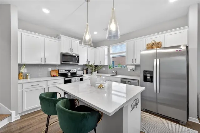 a kitchen with granite countertop a table chairs microwave and refrigerator