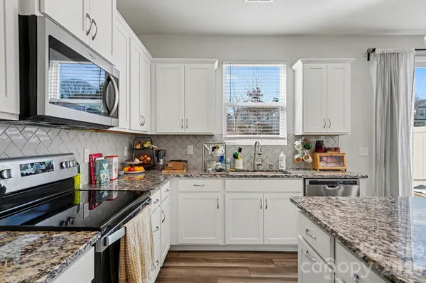 a kitchen with stainless steel appliances granite countertop a sink stove and cabinets
