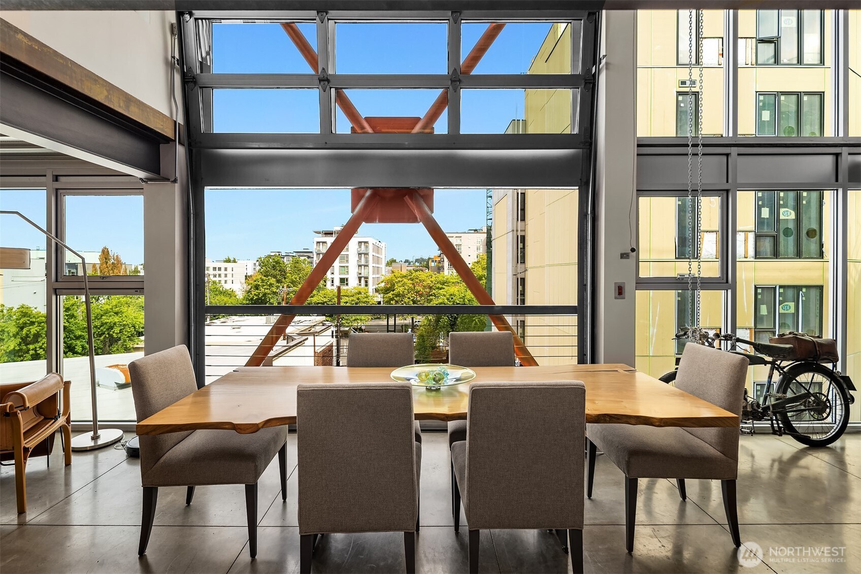 a view of a dining room with furniture large windows wooden floor and a potted plant