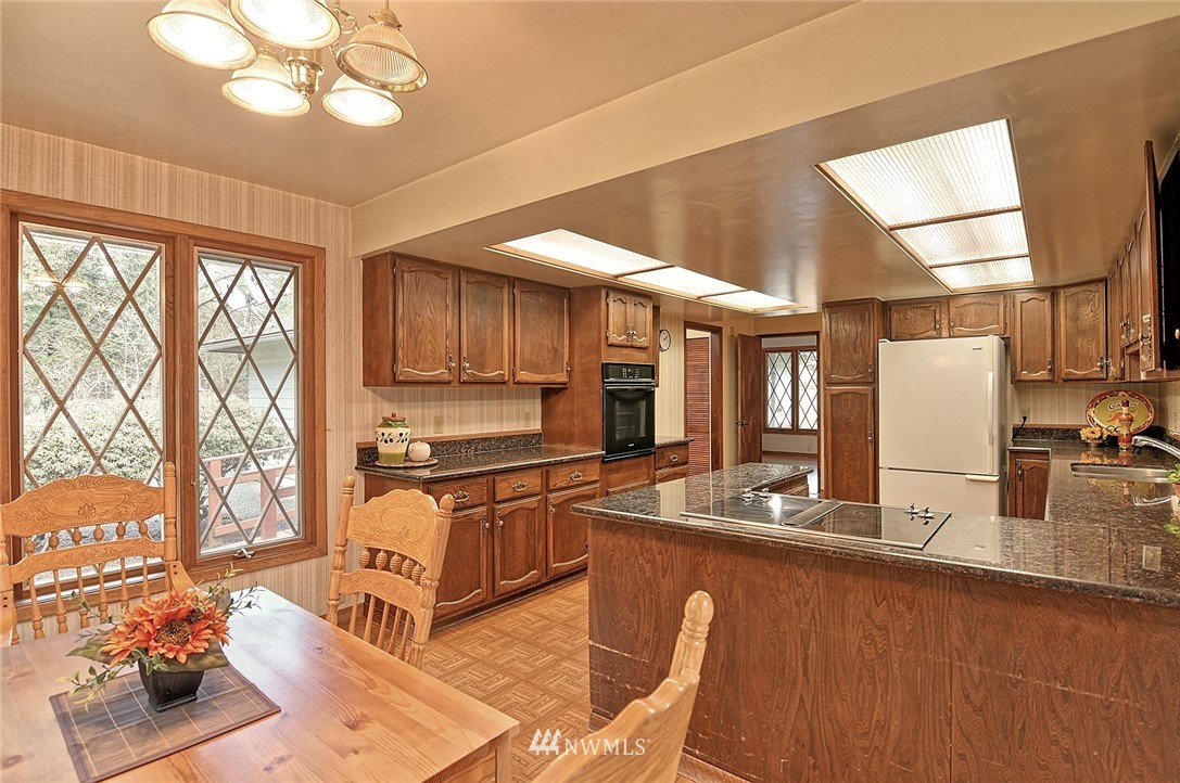 5011 228th Street Southeast Bothell, WA 98021 - Photo 8 of 40 a kitchen with stainless steel appliances granite countertop a stove a sink dishwasher and a refrigerator with wooden floor