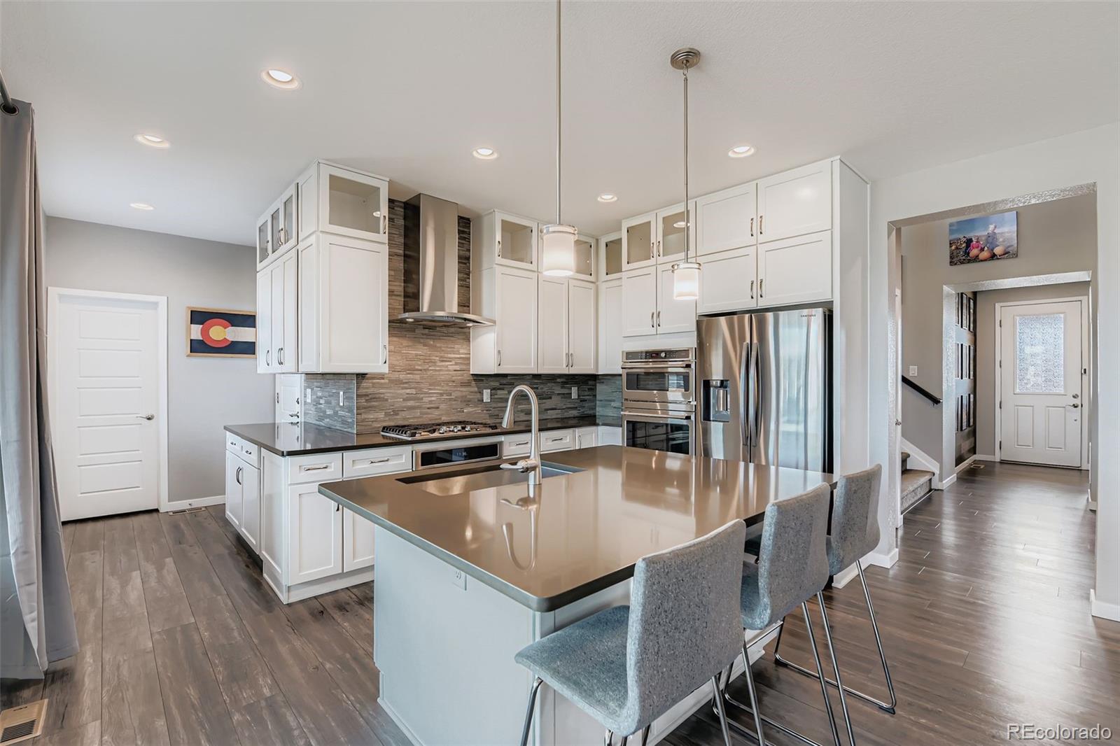 86 Nova Court Erie, CO 80516 - Photo 11 of 50 a kitchen with stainless steel appliances granite countertop a kitchen island hardwood floor sink stove and refrigerator