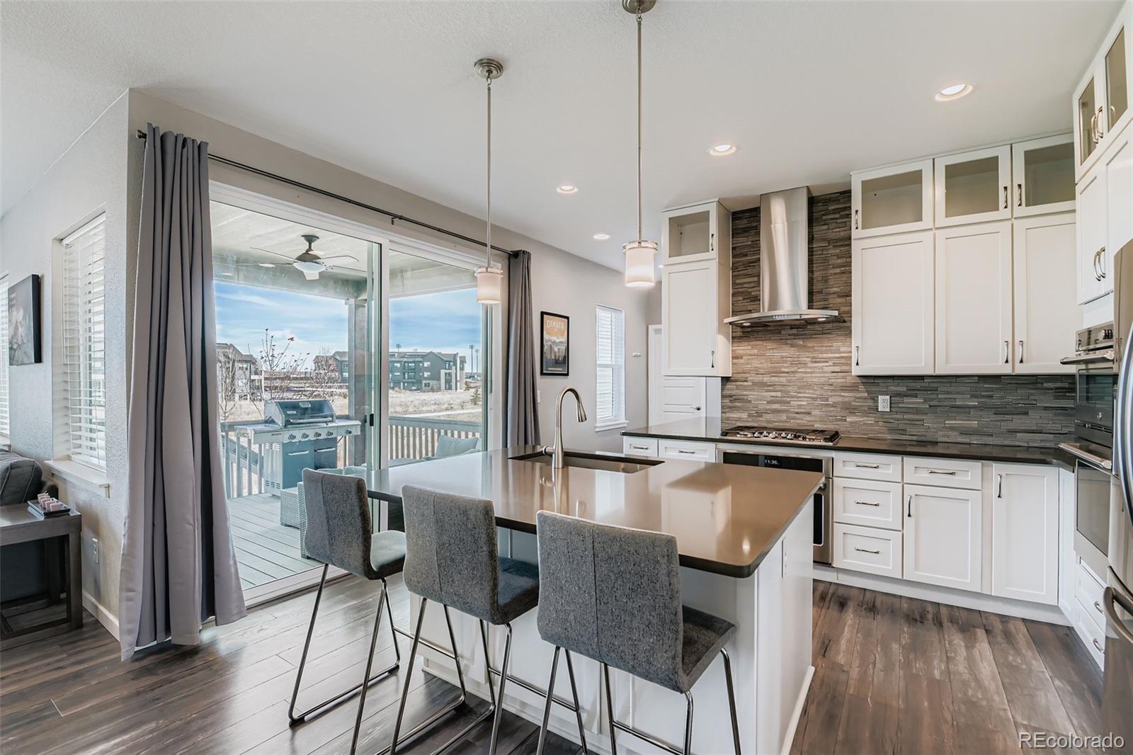 86 Nova Court Erie, CO 80516 - Photo 12 of 50 a kitchen with stainless steel appliances granite countertop a stove a refrigerator a sink and white cabinets with wooden floor