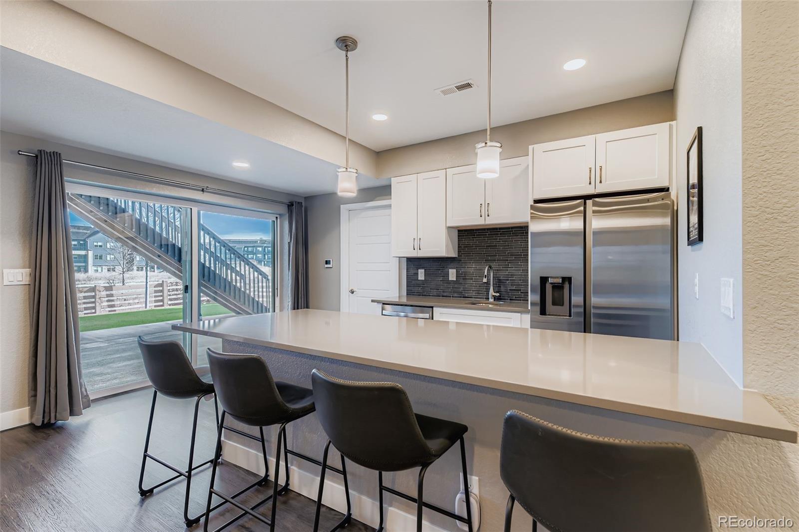 86 Nova Court Erie, CO 80516 - Photo 33 of 50 a kitchen with stainless steel appliances granite countertop a refrigerator a sink a stove a dining table and chairs