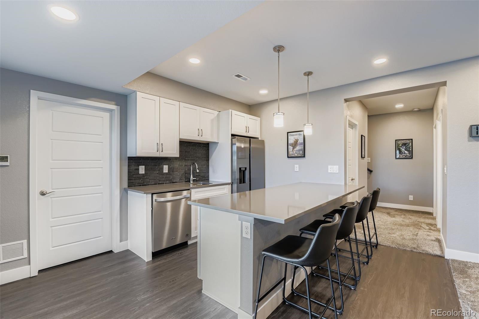 86 Nova Court Erie, CO 80516 - Photo 34 of 50 a kitchen with stainless steel appliances a stove a sink a refrigerator and white cabinets with wooden floor