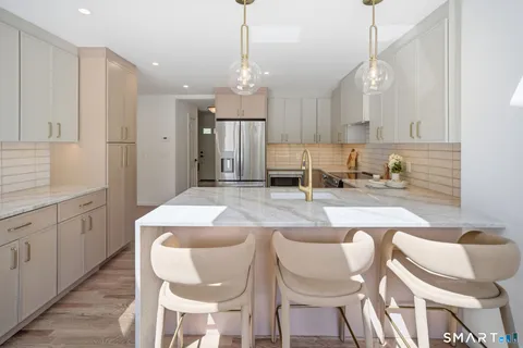an open kitchen with granite countertop a stove a sink a dining table and chairs with wooden floor