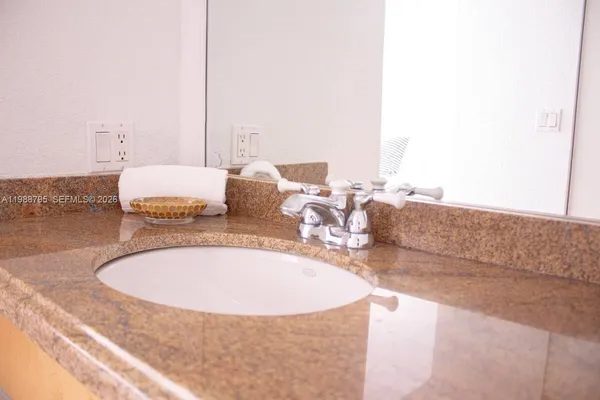 a bathroom with a granite countertop sink and a mirror