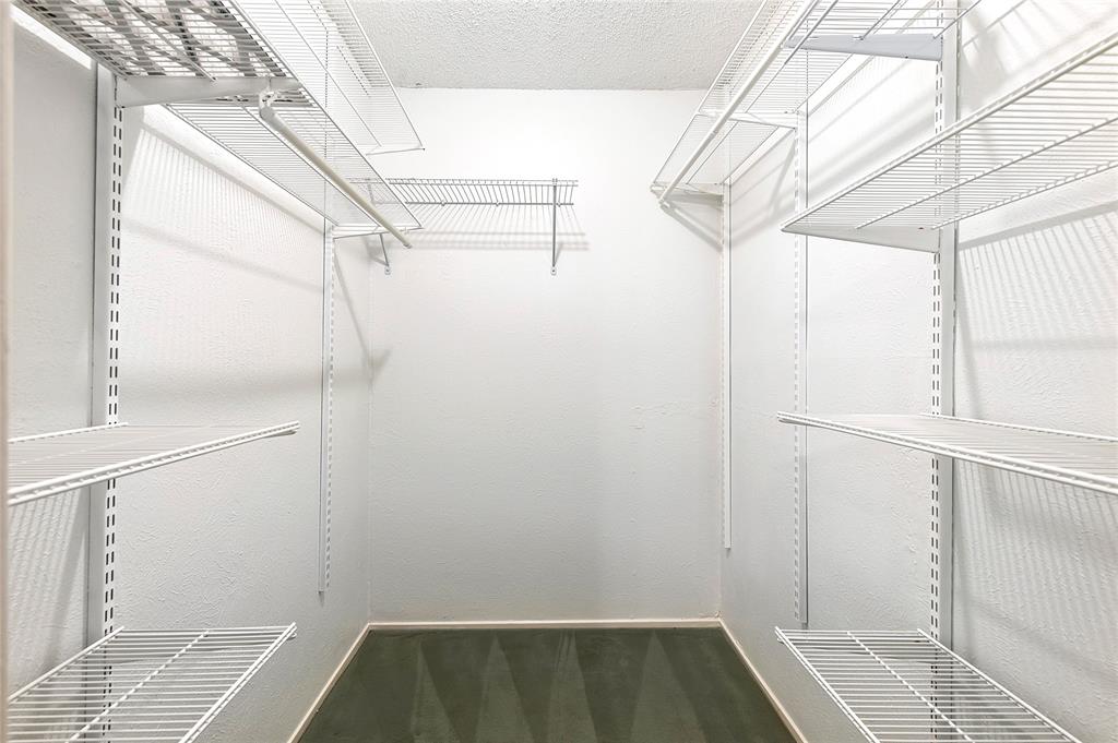 5626 Preston Oaks Road, Unit 5A Dallas, TX 75254 - Photo 6 of 20 Downstairs primary walk in closet, large and with custom shelving and racks.