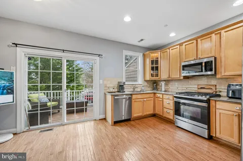 a kitchen with stainless steel appliances granite countertop wooden floors a stove a microwave a sink and dishwasher with wooden floor