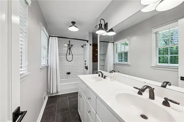 a bathroom with a double vanity sink a large mirror and a bathtub