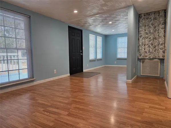 a view of an empty room with wooden floor and a window