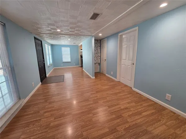 a view of empty room with wooden floor and fan
