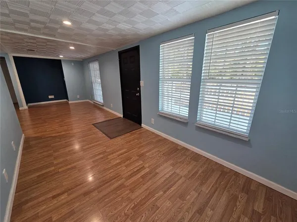 a view of an empty room with wooden floor and a window
