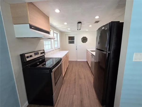 a kitchen with a refrigerator a sink and wooden floor