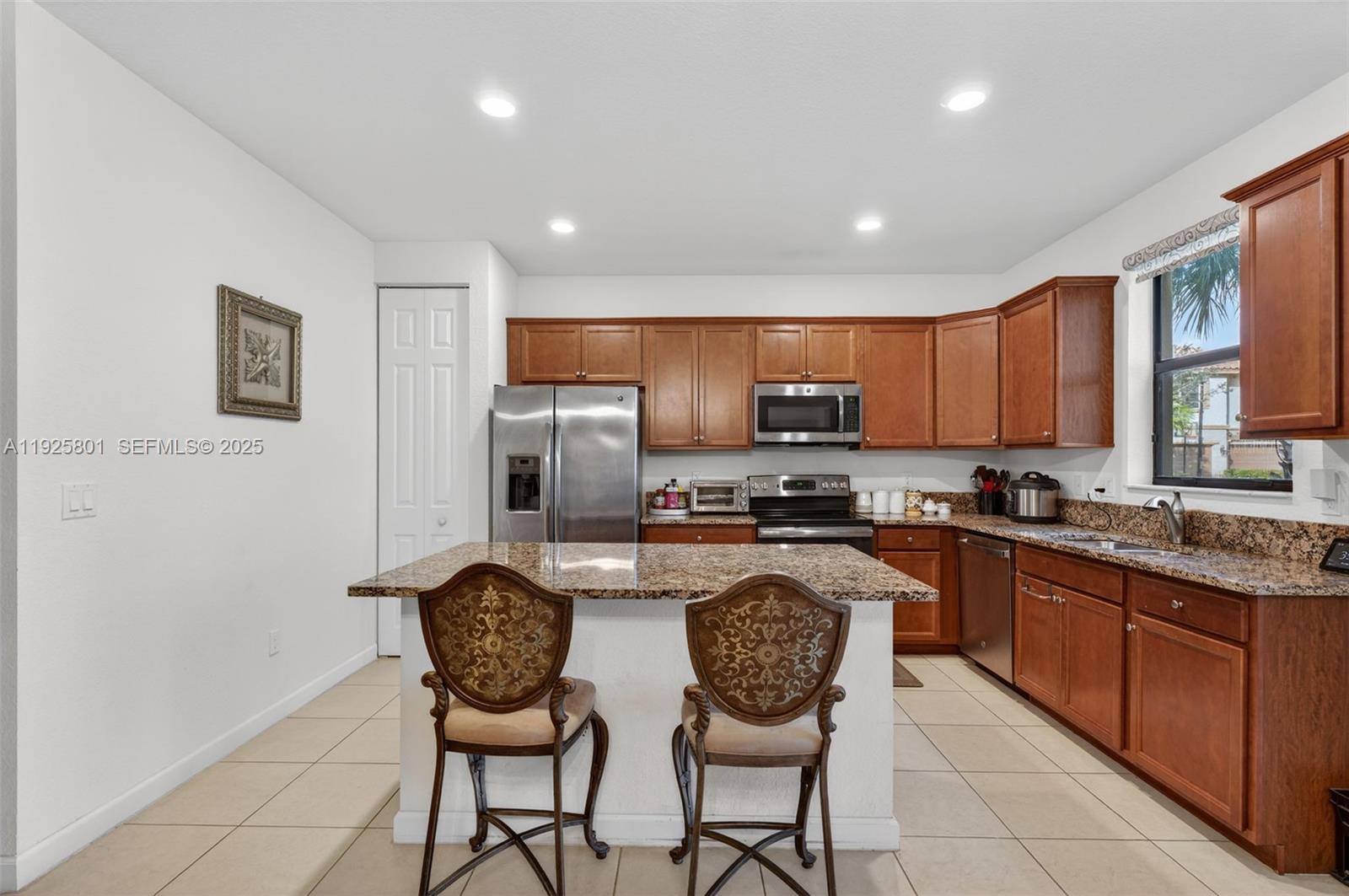 6978 Broadland Way Pompano Beach, FL 33073 - Photo 12 of 56 a kitchen with stainless steel appliances granite countertop a stove a refrigerator a sink dishwasher a dining table and chairs with wooden floor