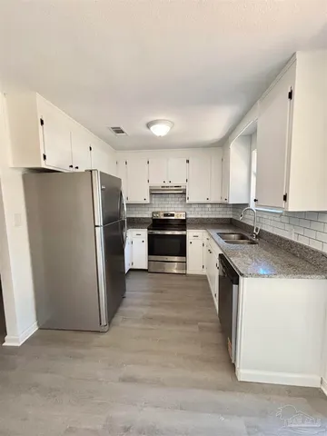 a kitchen with stainless steel appliances granite countertop a refrigerator a stove a sink and a microwave