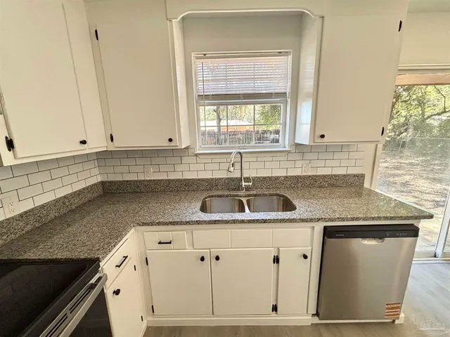 a kitchen with granite countertop a sink and cabinets