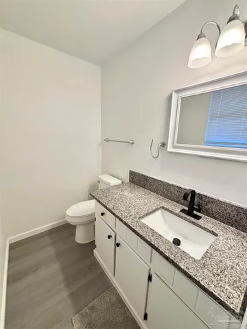 a bathroom with a granite countertop sink and a toilet