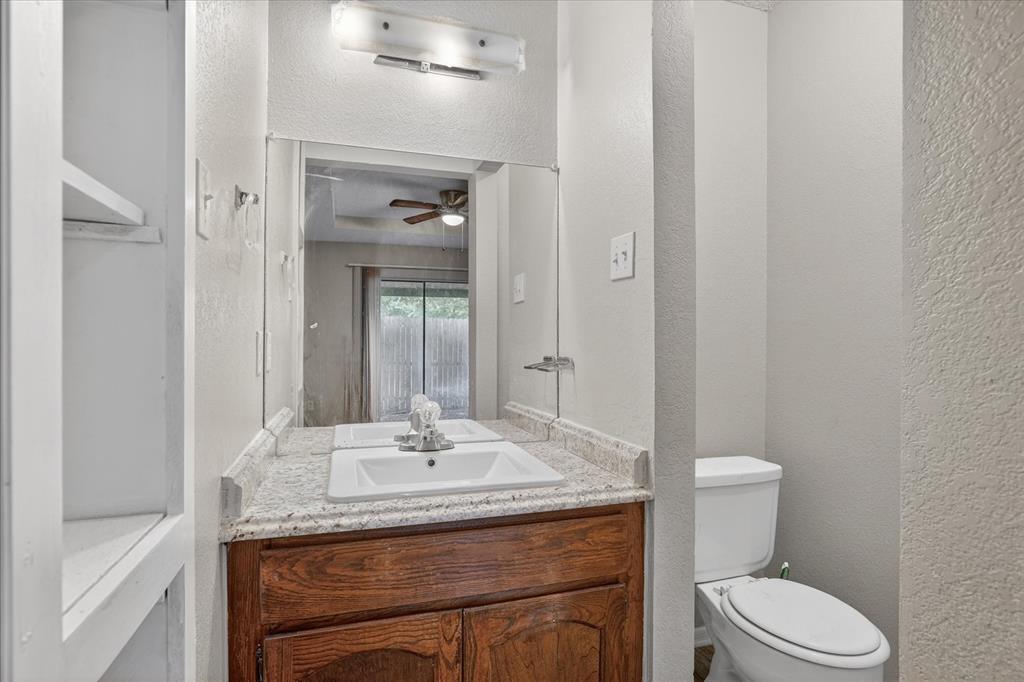119 Del Rio Avenue, Unit C Benbrook, TX 76126 - Photo 14 of 17 a bathroom with a granite countertop sink a toilet and a mirror