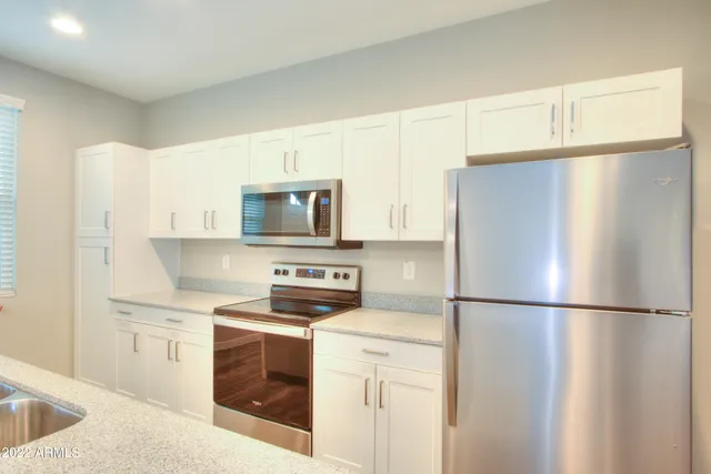 a kitchen with a refrigerator sink stove and cabinets