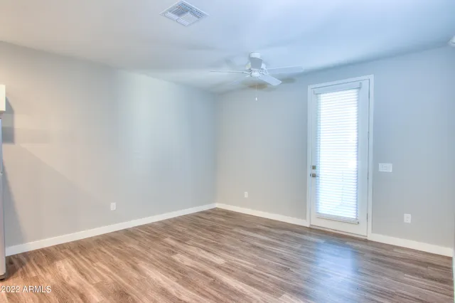 an empty room with wooden floor and ceiling fan