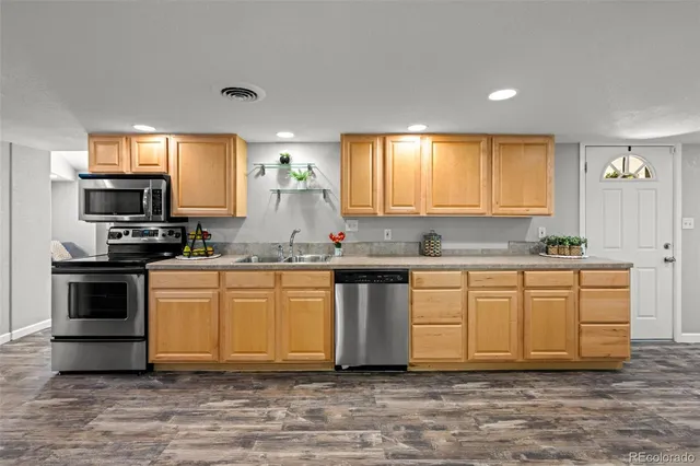 a kitchen with granite countertop a sink cabinets stainless steel appliances and a window