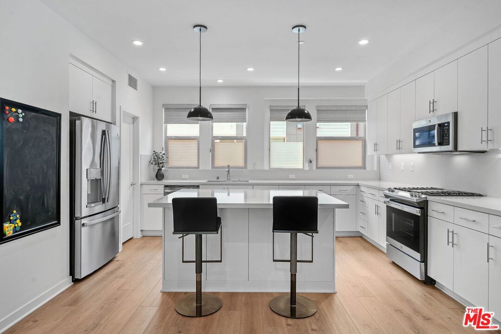 305 Placemark Irvine, CA 92614 - Photo 3 of 20 a kitchen with stainless steel appliances kitchen island granite countertop a refrigerator a stove a oven and a wooden floor