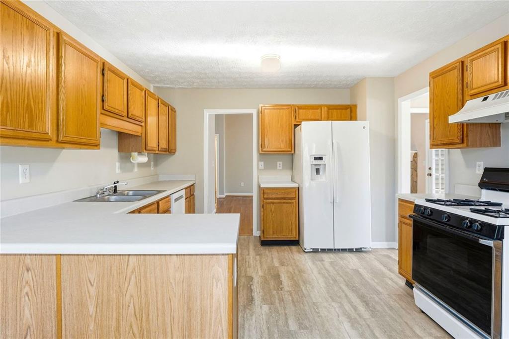 4099 Harvest Ridge Drive Douglasville, GA 30135 - Photo 17 of 46 a kitchen with stainless steel appliances a stove a refrigerator a sink a oven with wooden floor and cabinets