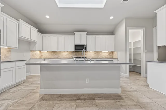 a kitchen with kitchen island granite countertop a stove a sink a counter top space and cabinets