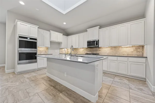 a kitchen with granite countertop a stove top oven and cabinets
