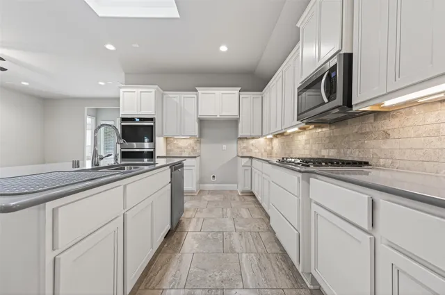 a large kitchen with stainless steel appliances granite countertop white cabinets a sink and dishwasher
