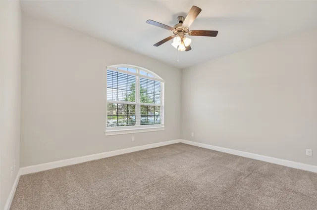 an empty room with a chandelier fan and windows