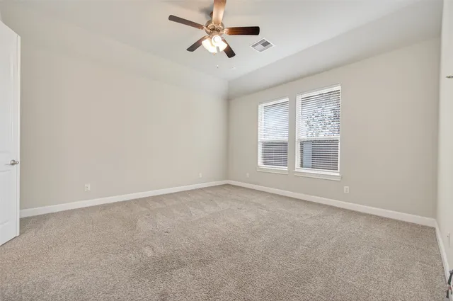 an empty room with windows and fan