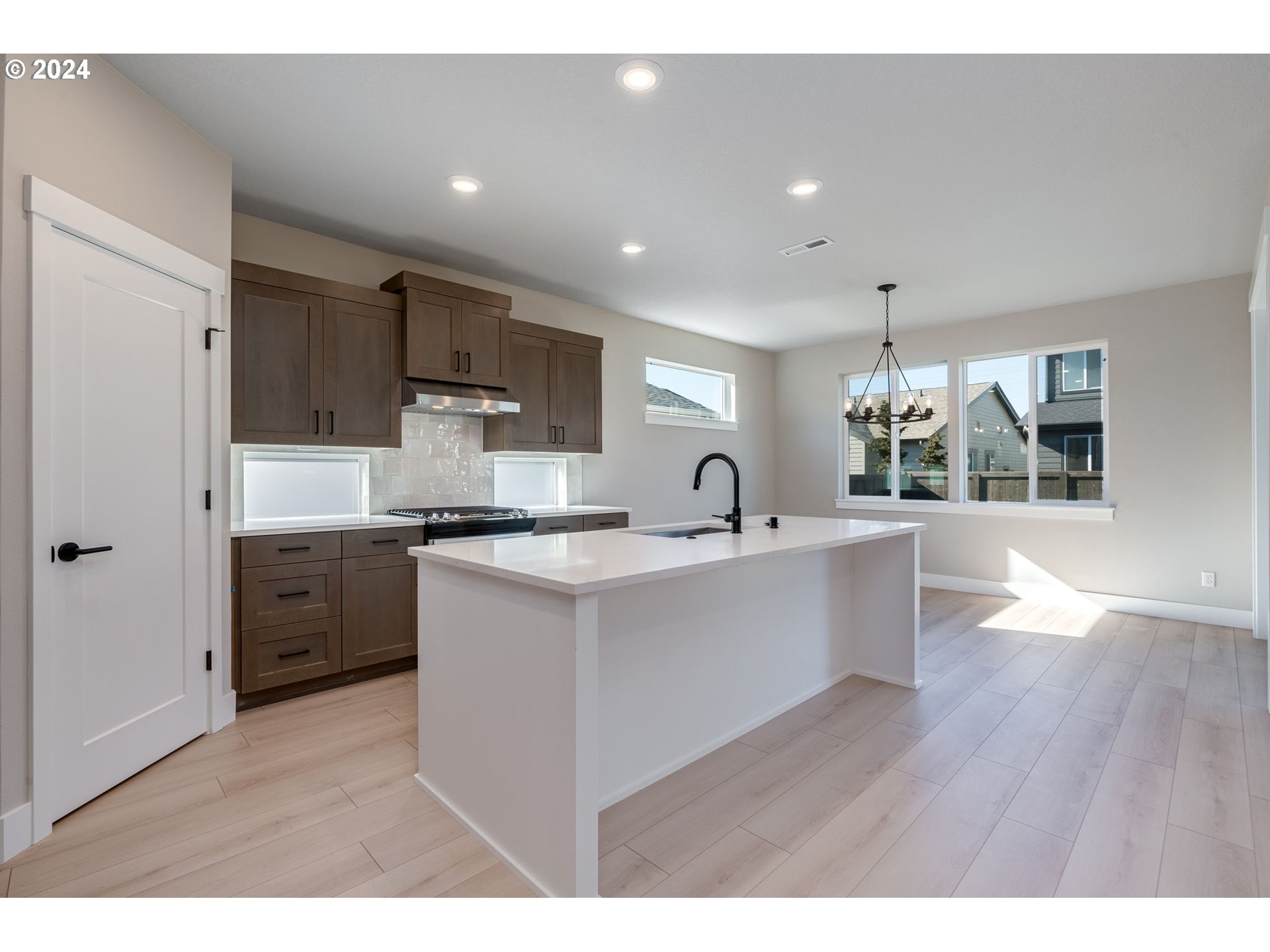 3703 South Arwana Lane Ridgefield, WA 98642 - Photo 18 of 35 a large white kitchen with wooden floors and stainless steel appliances