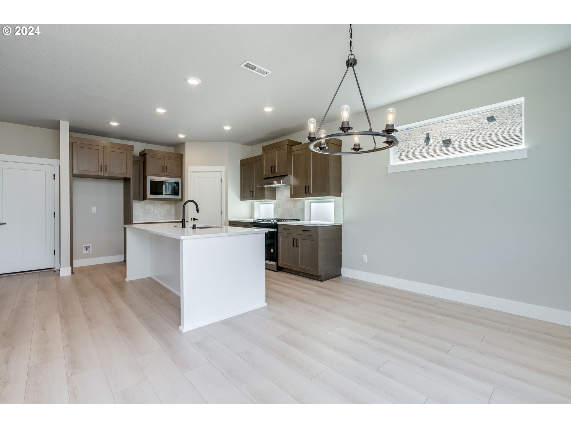 3703 South Arwana Lane Ridgefield, WA 98642 - Photo 24 of 35 a living room with stainless steel appliances kitchen island a chandelier and a view of kitchen