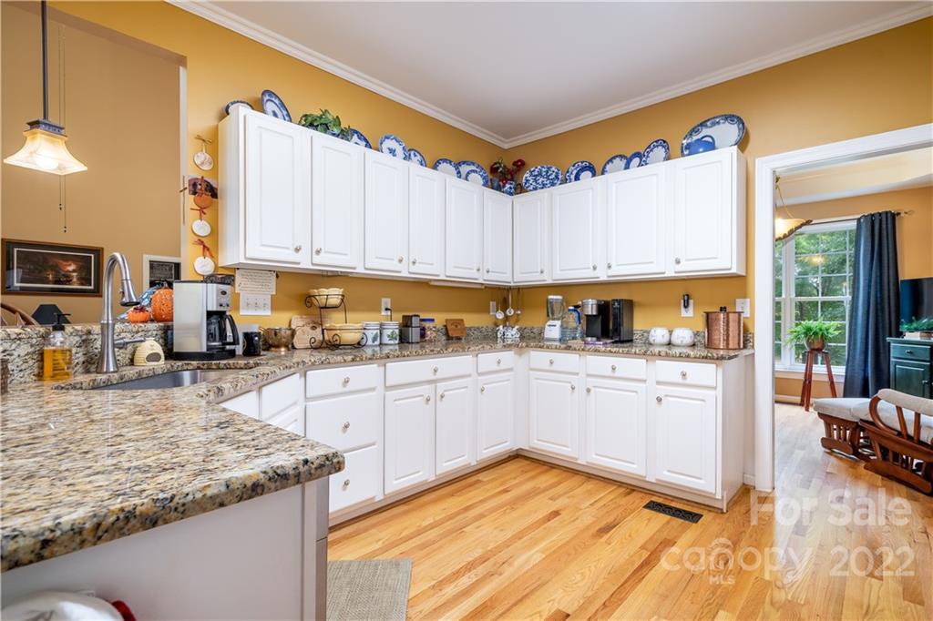 7545 Windy Pine Circle, Unit 30 Denver, NC 28037 - Photo 10 of 38 a kitchen with granite countertop wooden cabinets a sink and dishwasher a stove with wooden floor