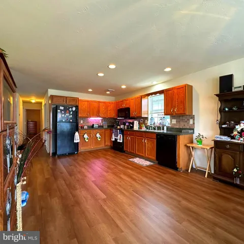 a living room with stainless steel appliances furniture and kitchen view
