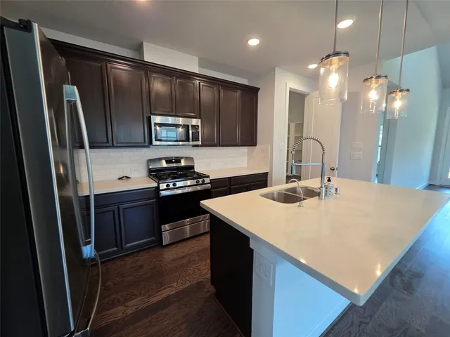a kitchen with kitchen island granite countertop a sink stove and refrigerator