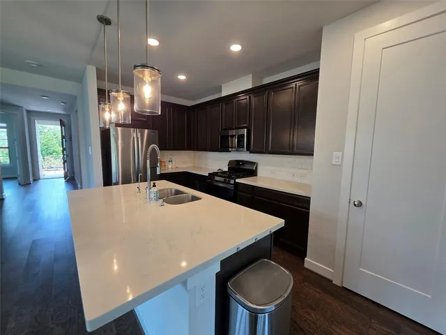a kitchen with a table chairs refrigerator and wooden floor