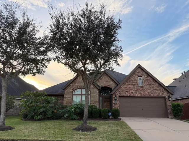 a front view of a house with a garden and trees