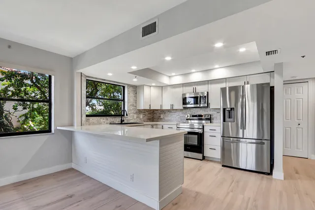 a kitchen with stainless steel appliances granite countertop a refrigerator and a stove top oven