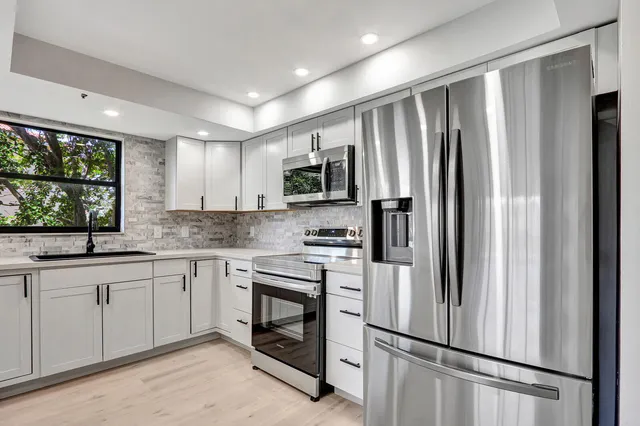 a kitchen with granite countertop stainless steel appliances a refrigerator sink and microwave